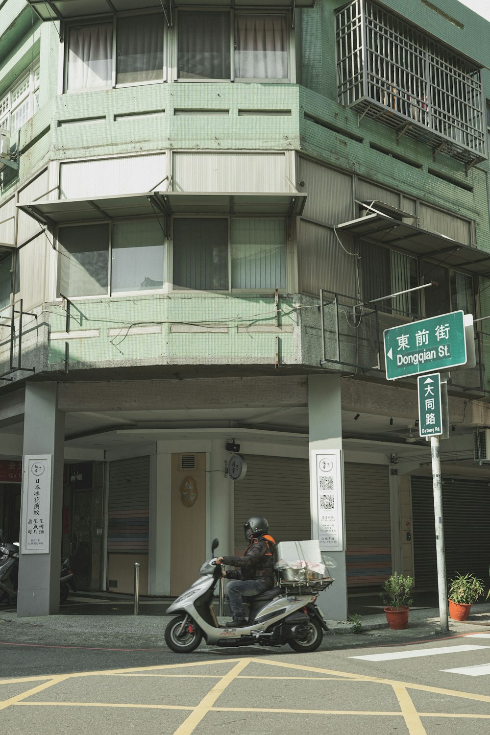 a man riding a motorcycle down a street next to a tall building