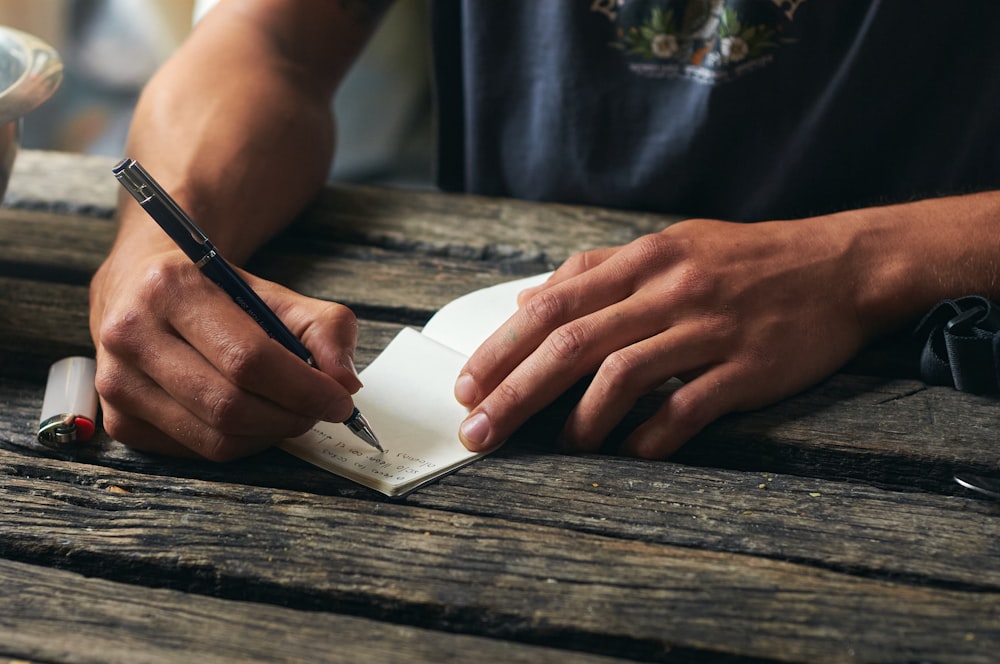 a person writing on a piece of paper with a pen