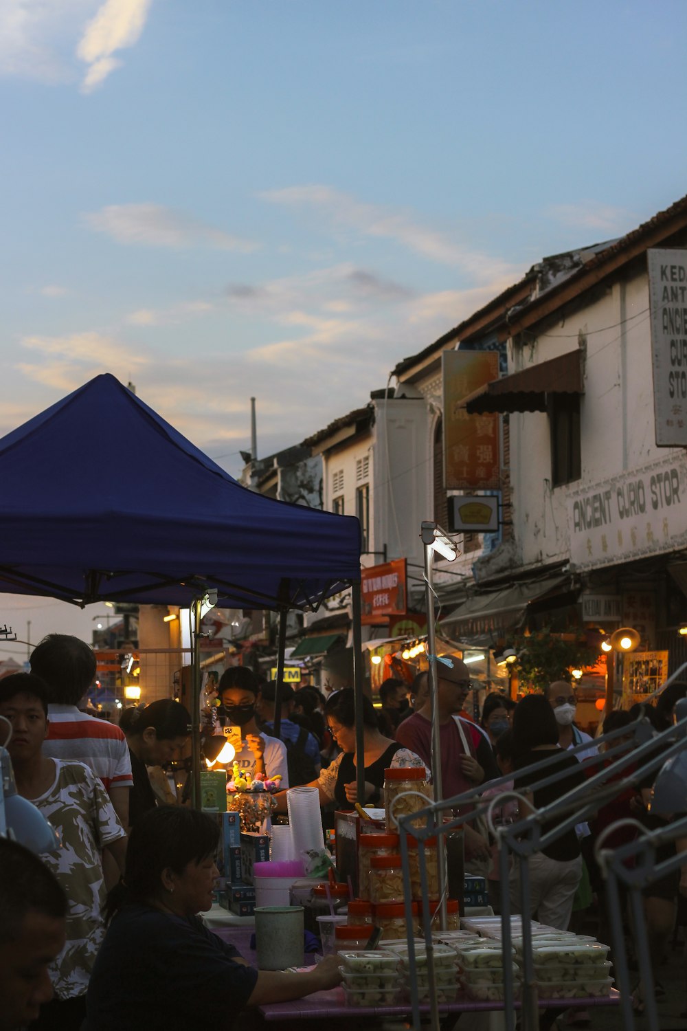 a group of people sitting at a table under a blue umbrella