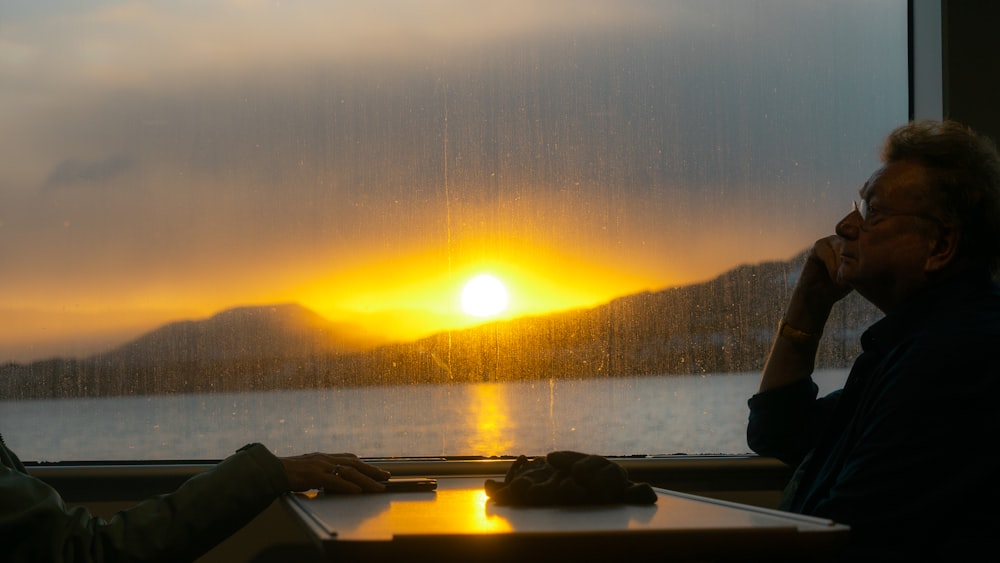 a couple of people sitting at a table in front of a window