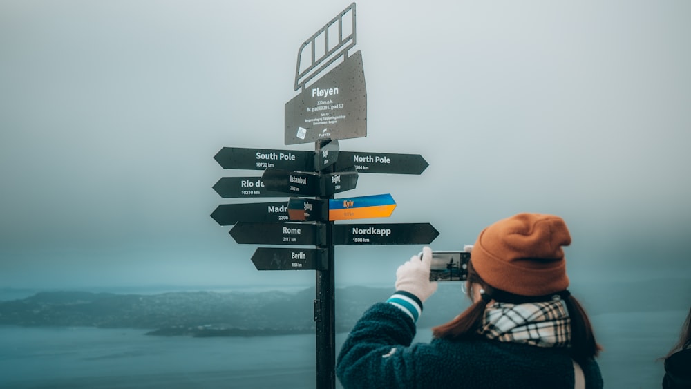 a person taking a picture of a sign post