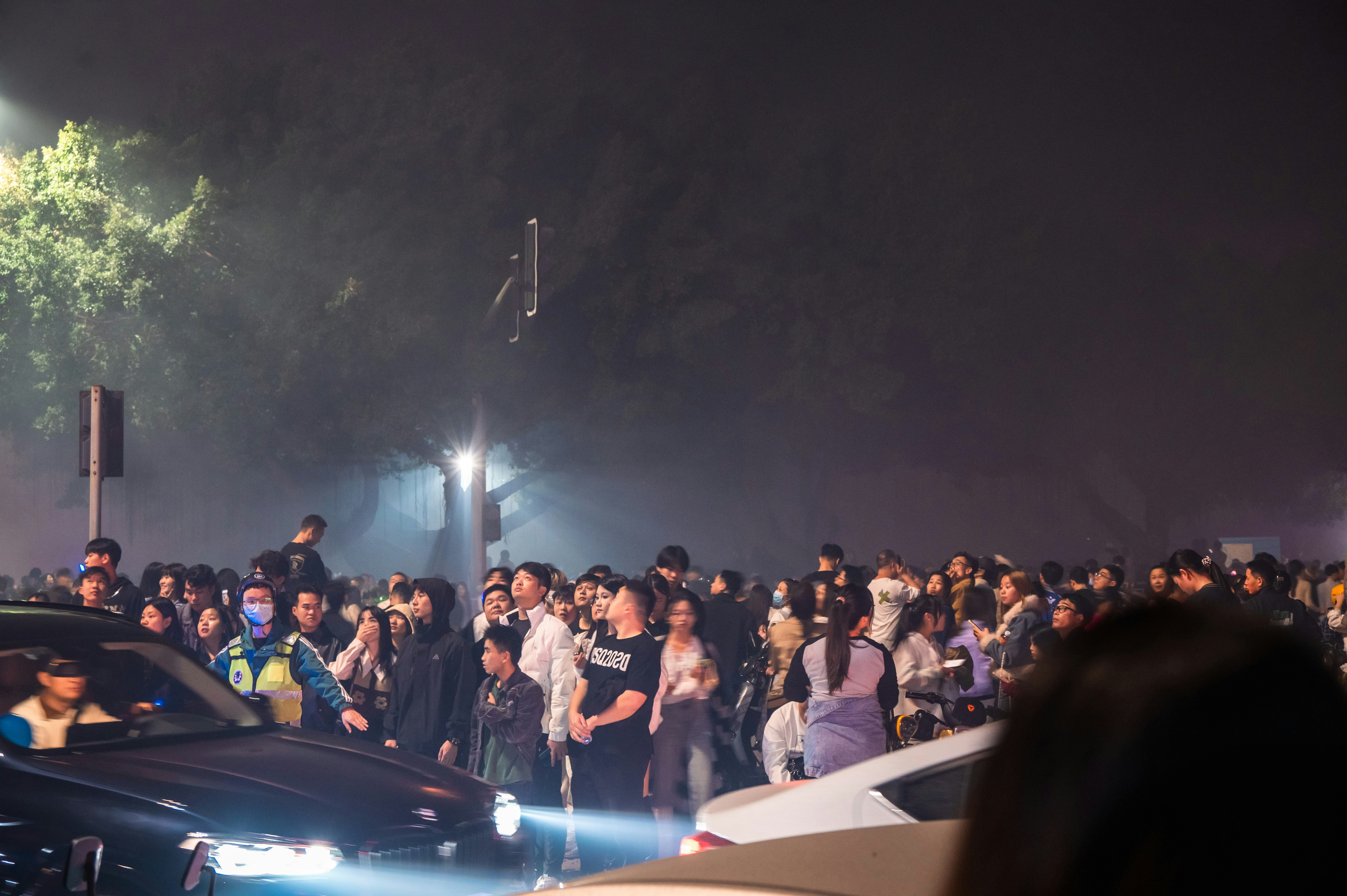 a crowd of people standing around a car at night