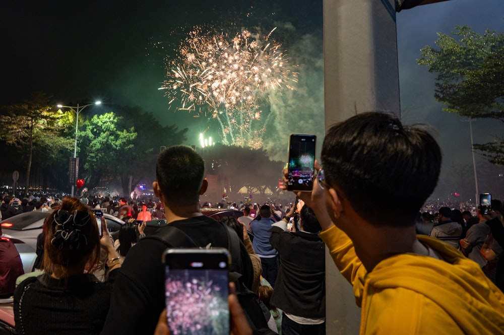 a group of people taking pictures of fireworks