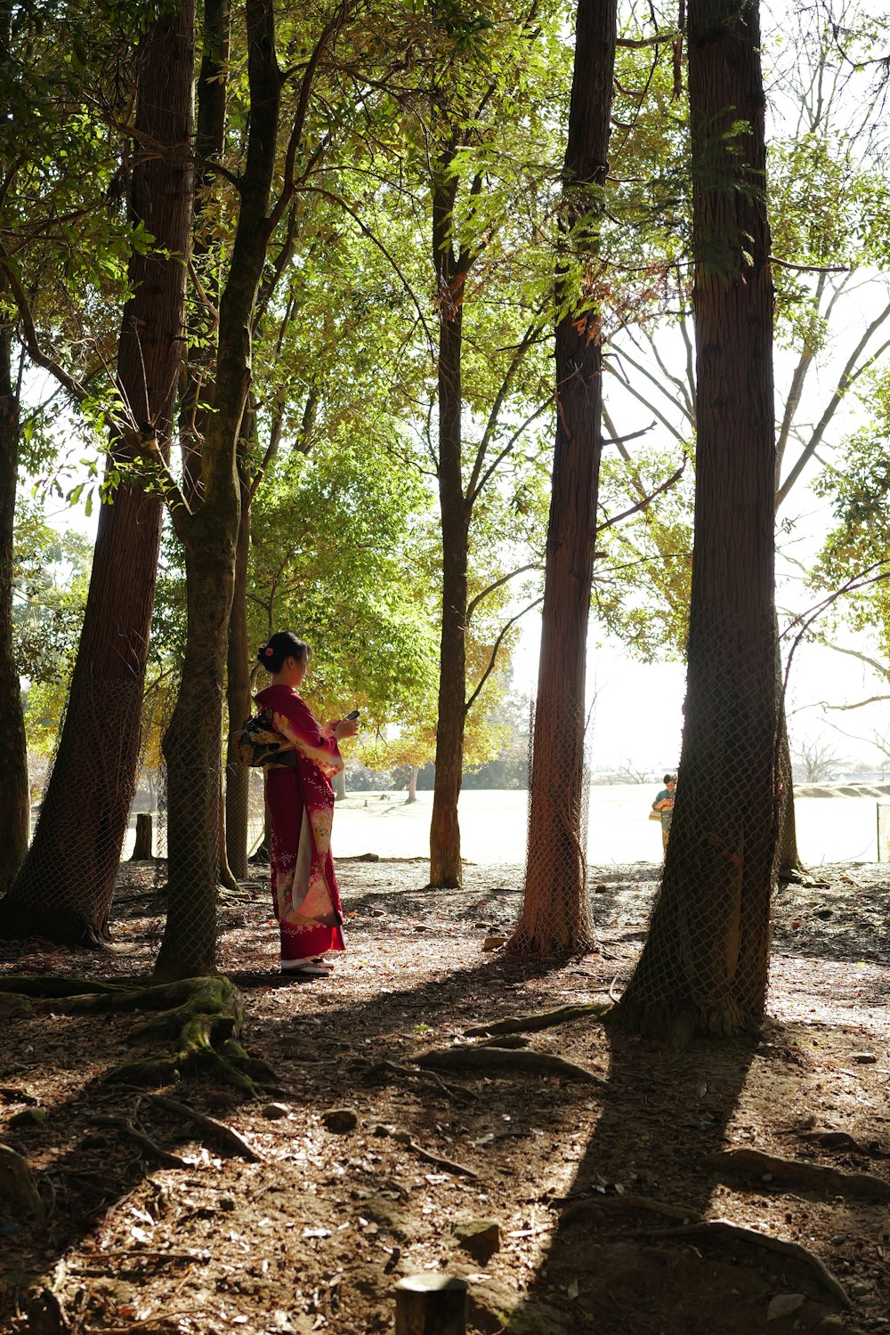 a woman in a red dress standing in a forest