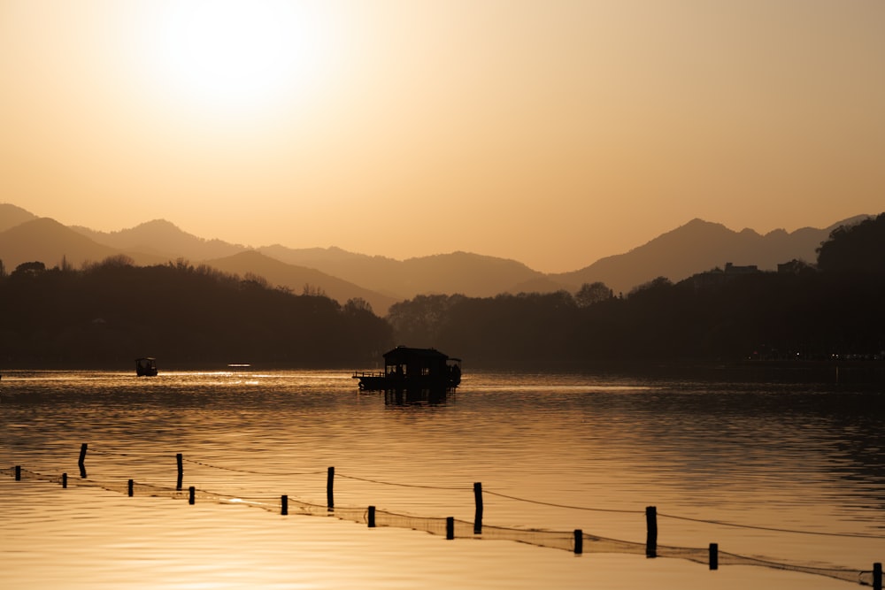 a boat floating on top of a lake at sunset