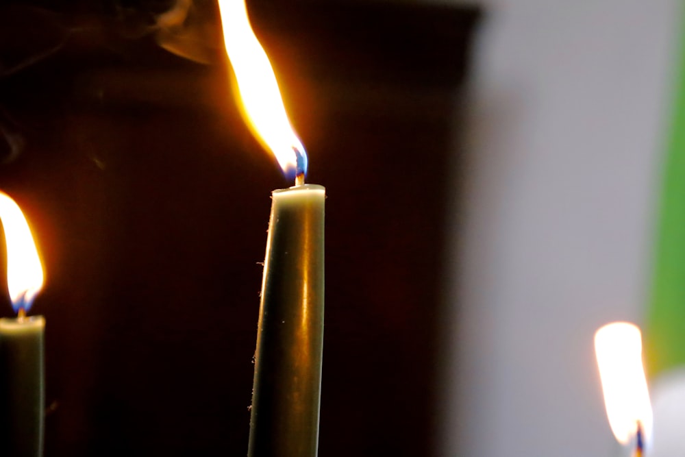 a close up of two lit candles with a blurry background