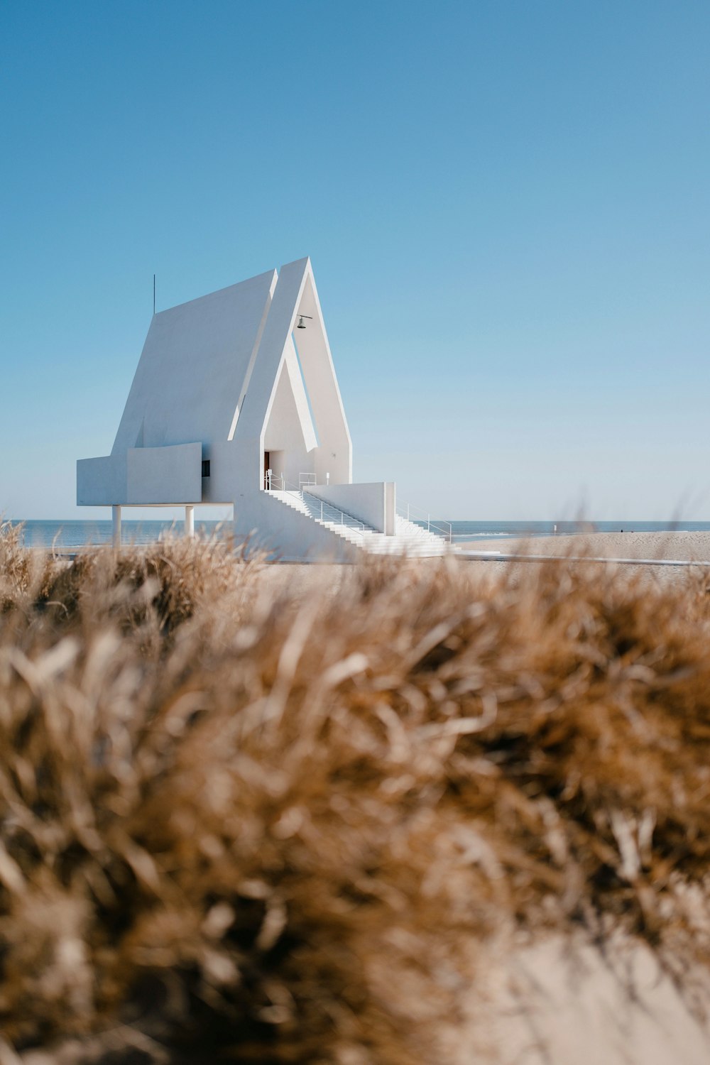 a white house sitting on top of a sandy beach