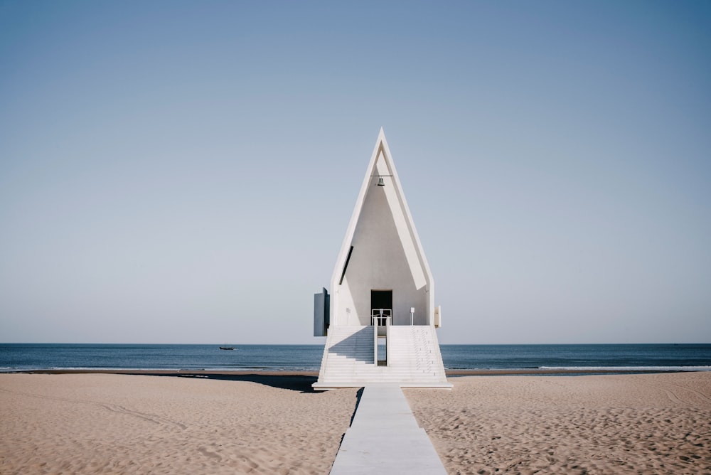 a very tall white structure sitting on top of a sandy beach