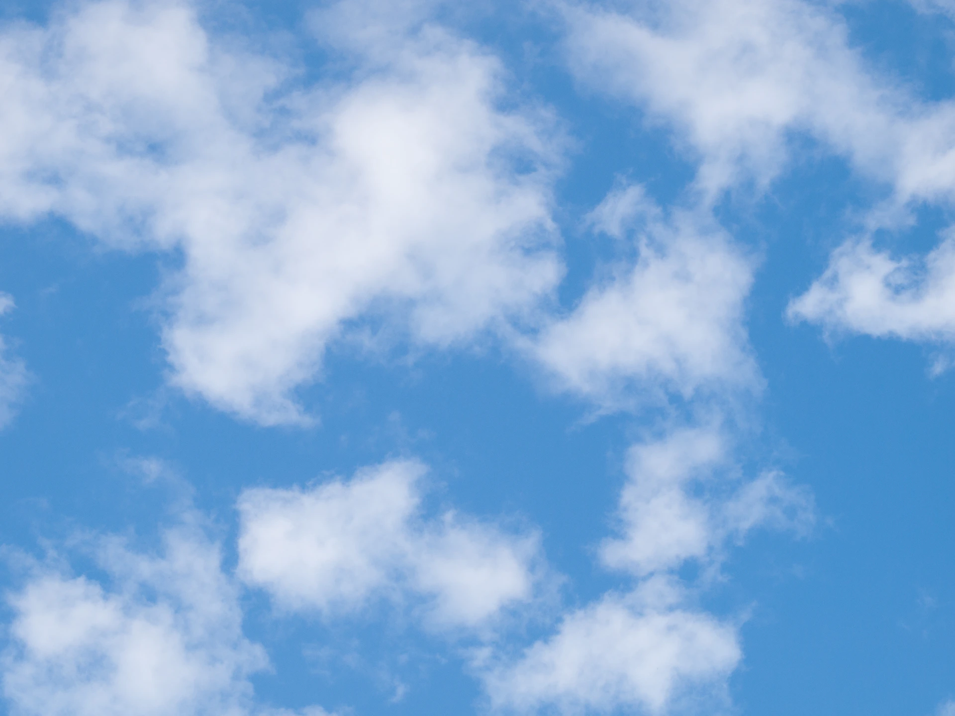 a plane flying through a blue cloudy sky