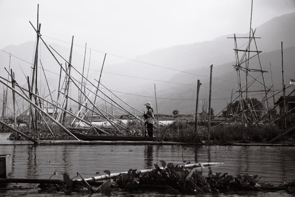 a black and white photo of a man standing on a dock