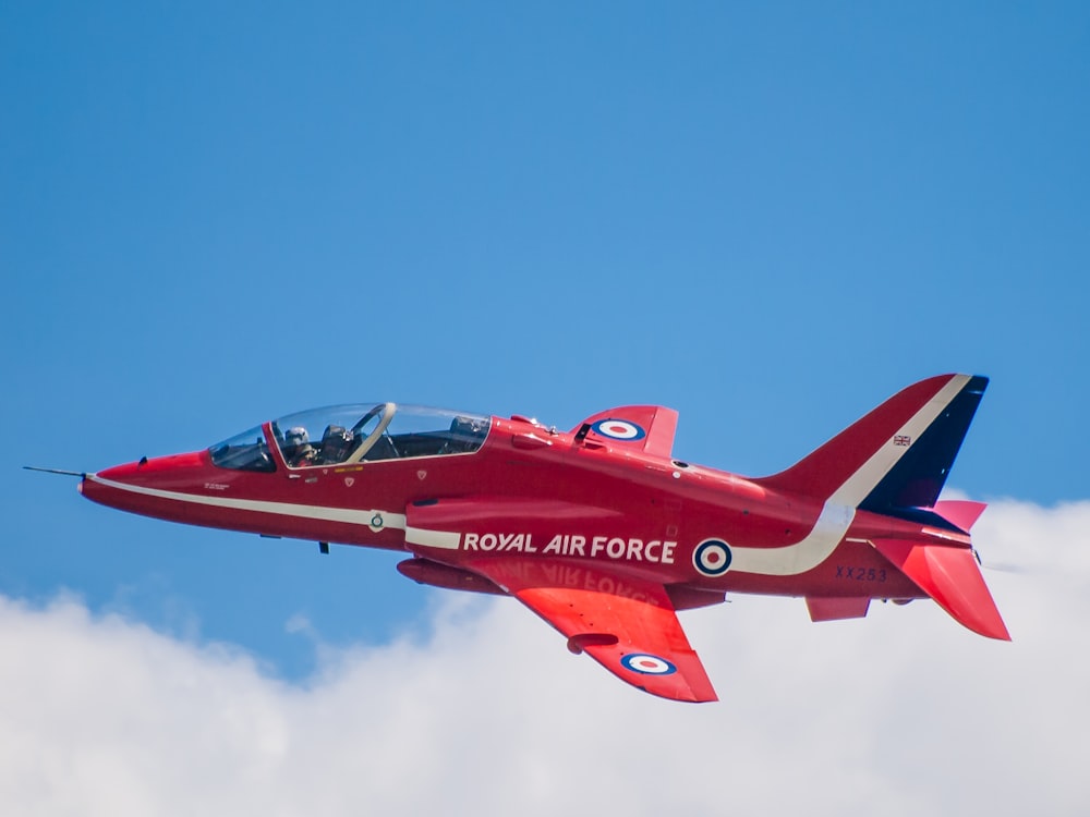 Ein roter Kampfjet, der durch einen blauen Himmel fliegt