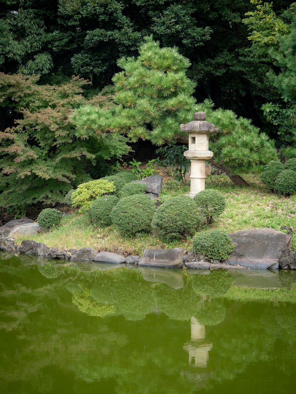 a pond with rocks and a stone lantern in the middle of it