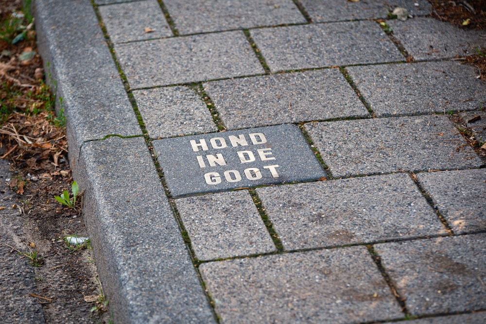 a brick sidewalk with a hand in de got sign on it