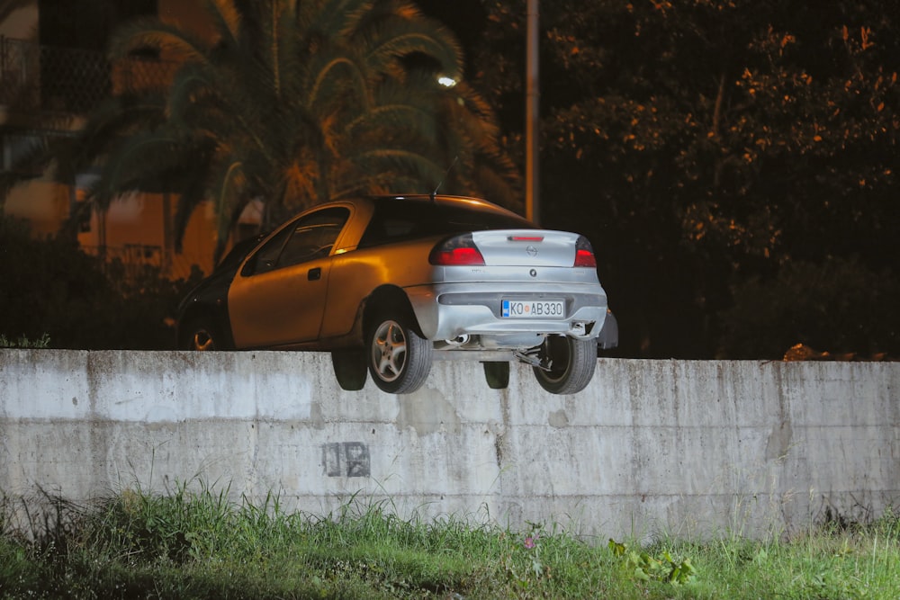 a silver car is upside down on a concrete wall
