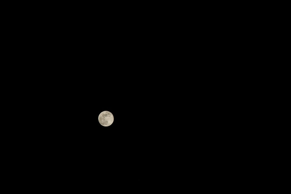 a full moon is seen in the dark sky