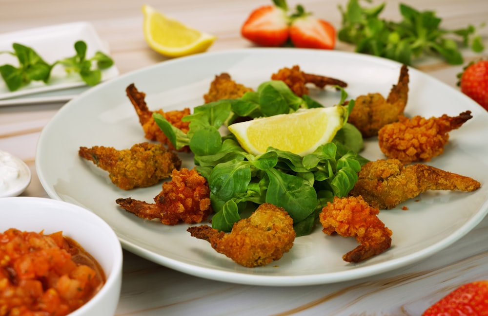 a white plate topped with fried shrimp next to a bowl of salad