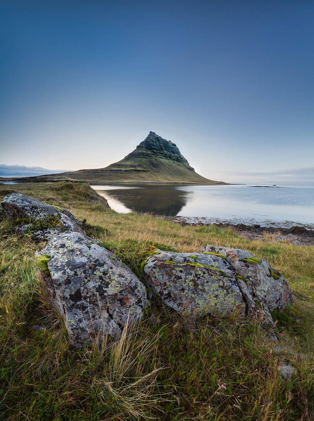 a large rock sitting on top of a lush green field