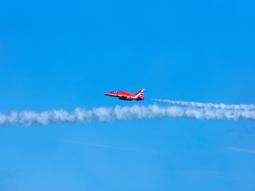 a red and white jet flying through a blue sky