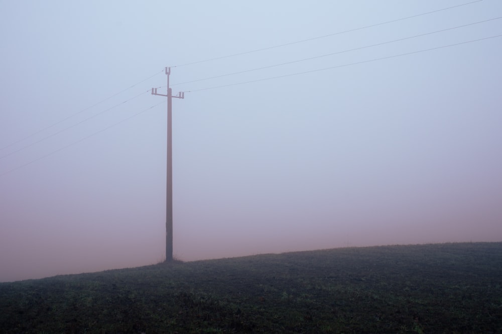 a telephone pole on a hill in the fog