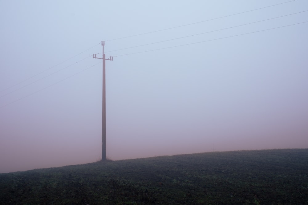 ein Telefonmast auf einem Hügel im Nebel