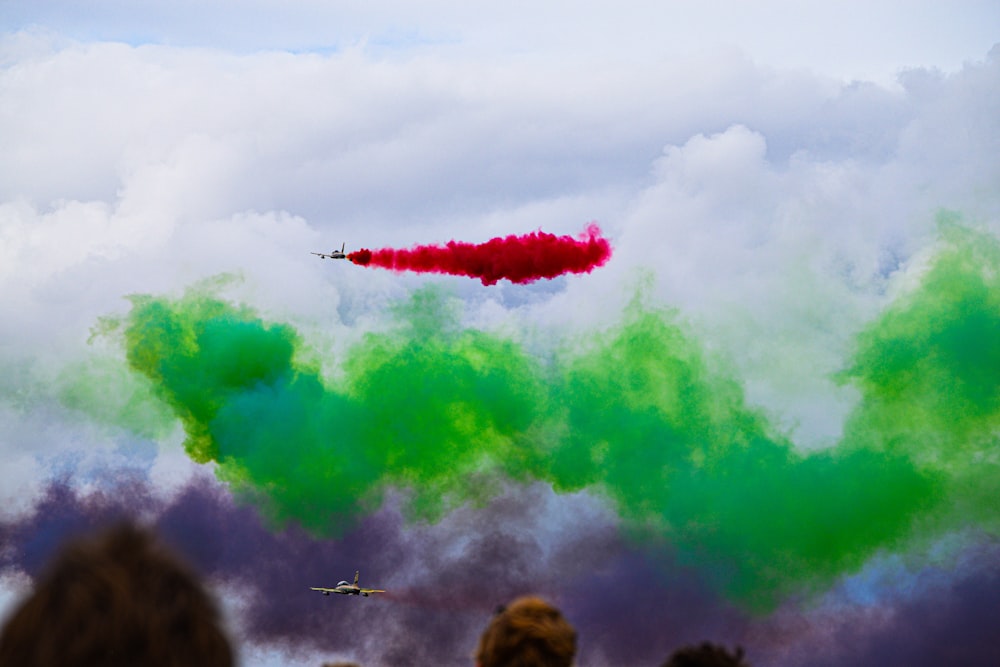 a group of people watching a red and green smoke bomb