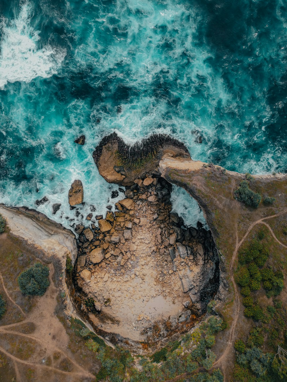 an aerial view of the ocean and rocks