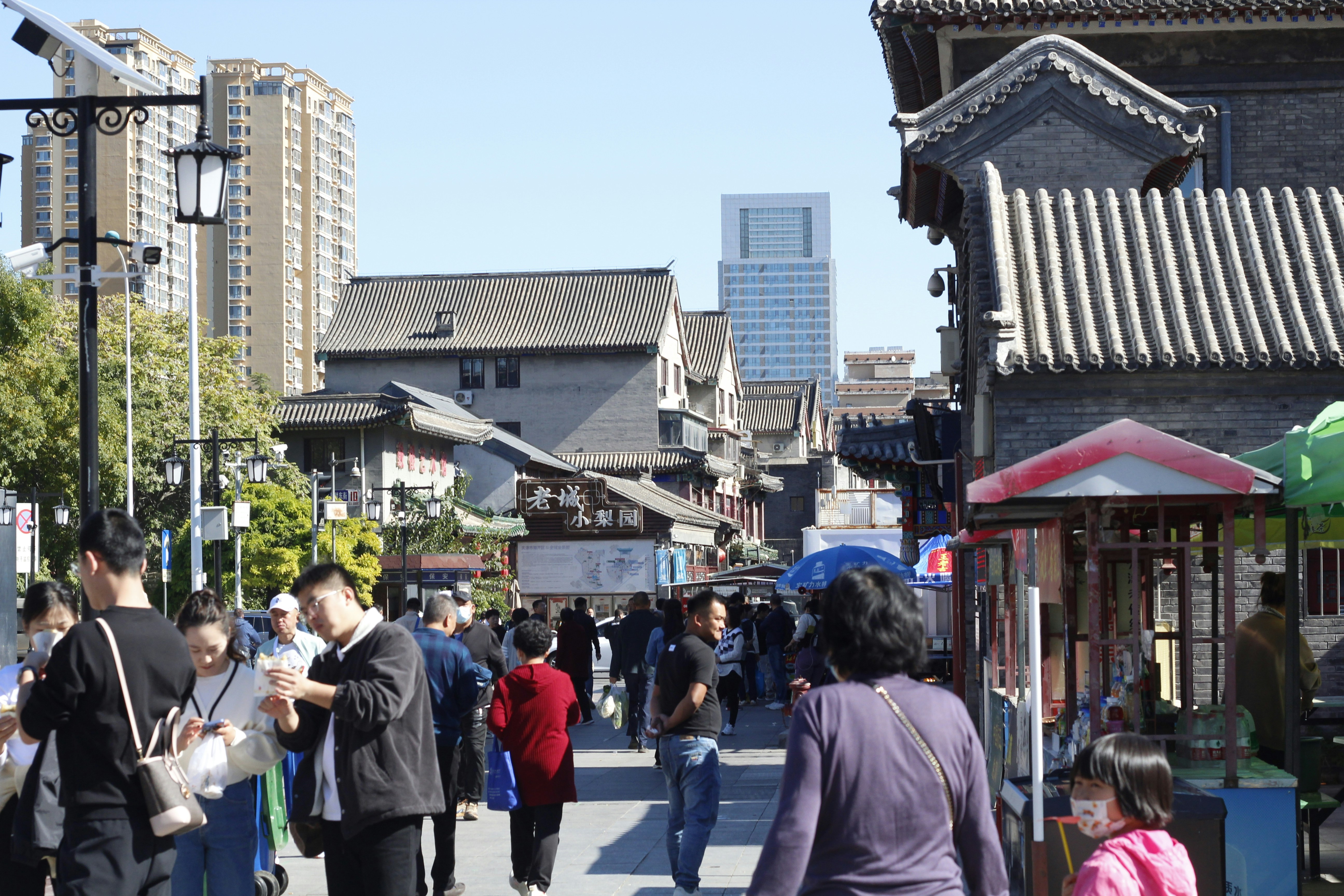 高層ビルの隣の通りを歩いている人々のグループ