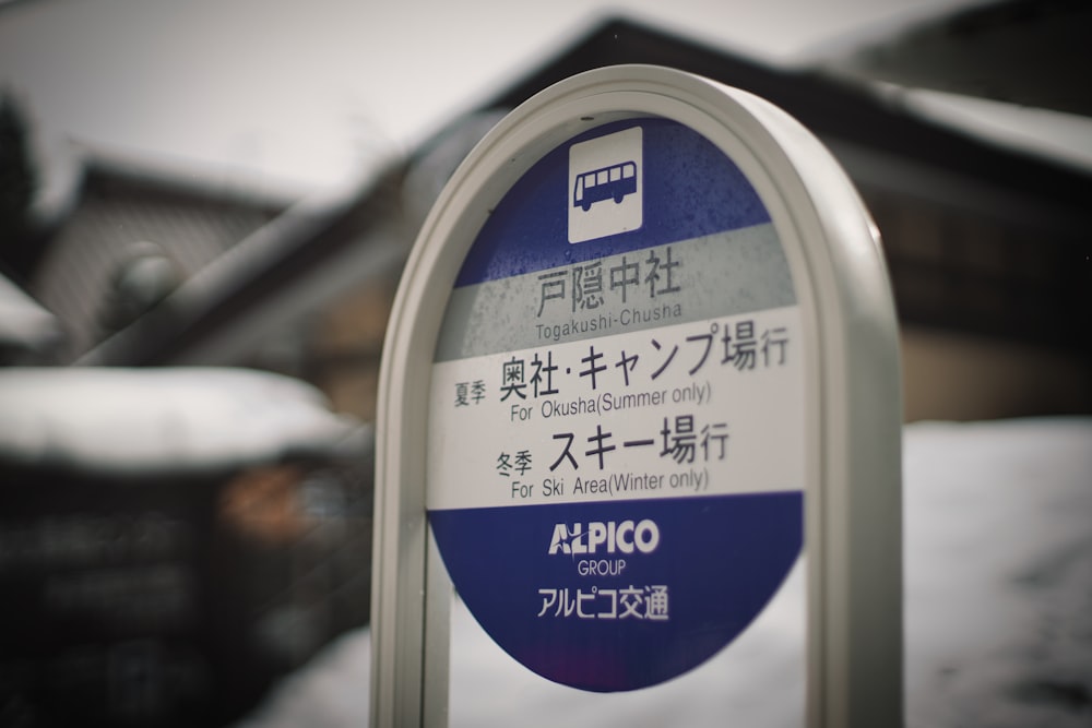 a blue and white parking meter sitting in the snow