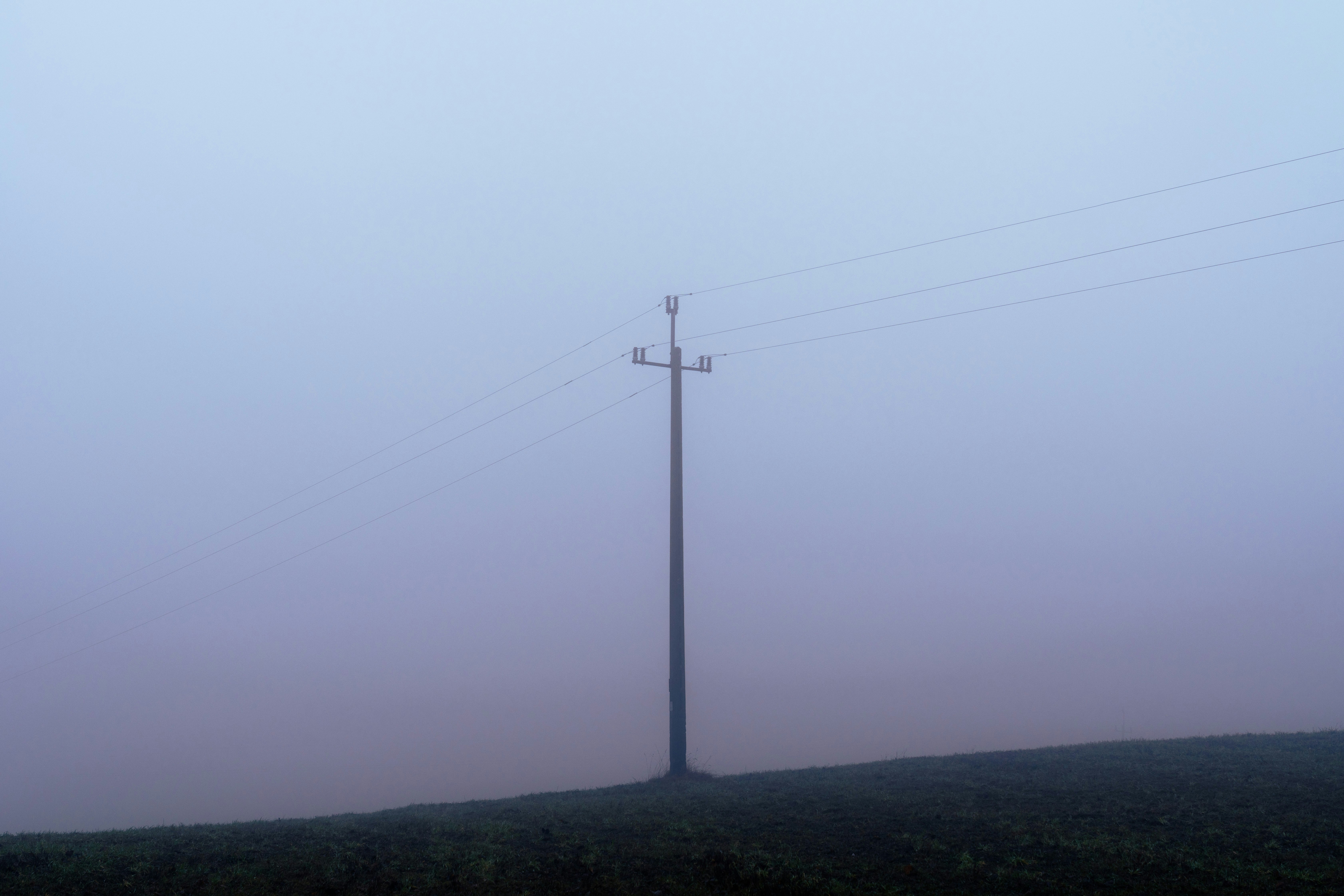a telephone pole in the fog on a hill