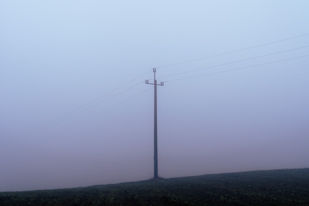 a telephone pole in the fog on a hill