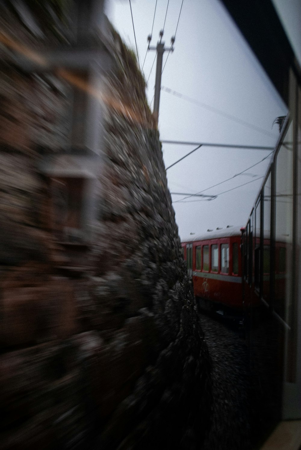 a red train traveling down train tracks next to a stone wall