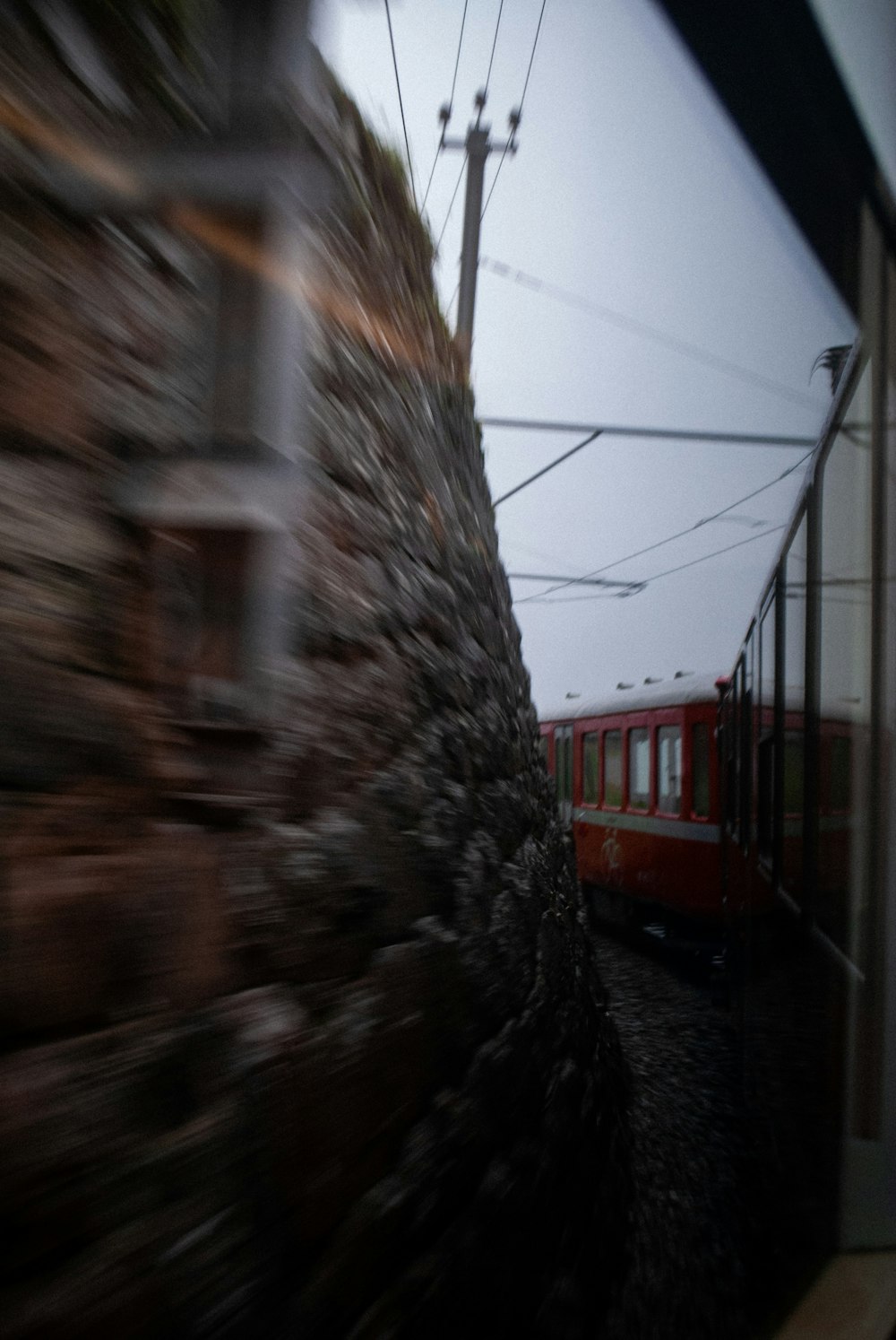 Ein roter Zug, der neben einer Steinmauer auf Bahngleisen fährt