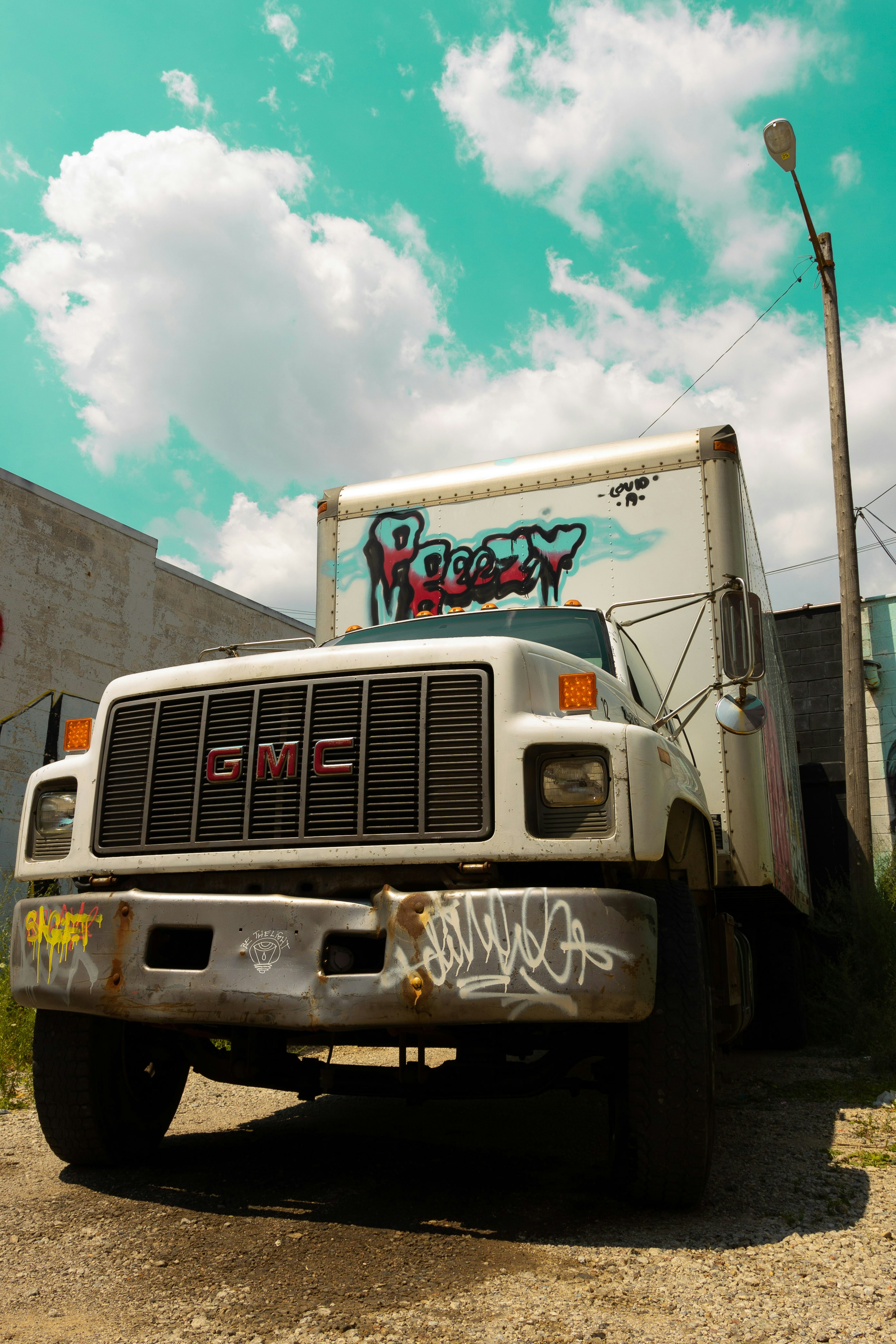 um caminhão branco com pichações estacionado em uma estrada de terra