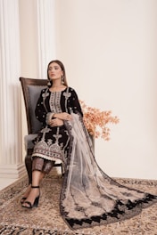 a woman sitting on a chair in a black dress
