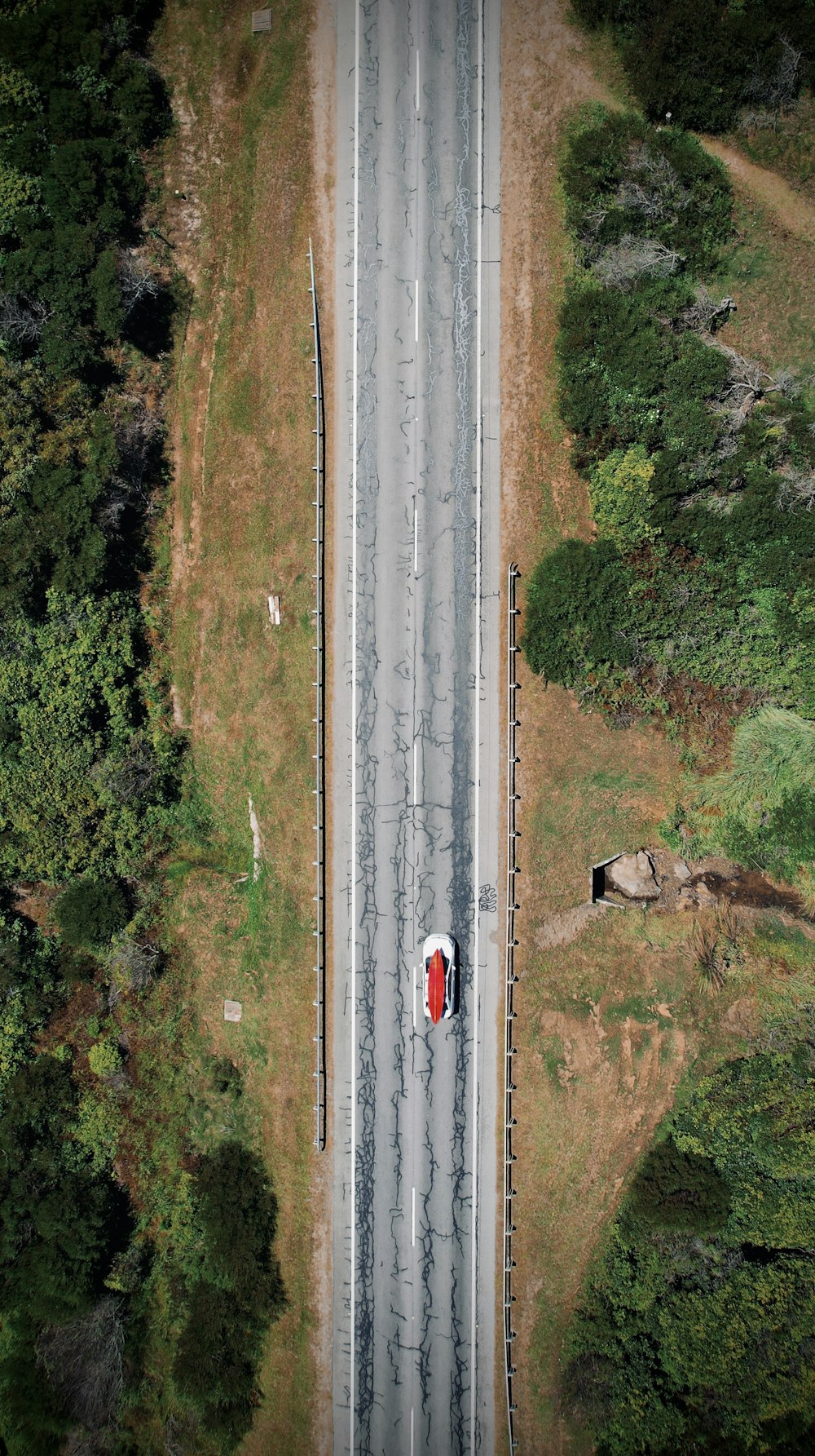 an aerial view of a road with a red car on it