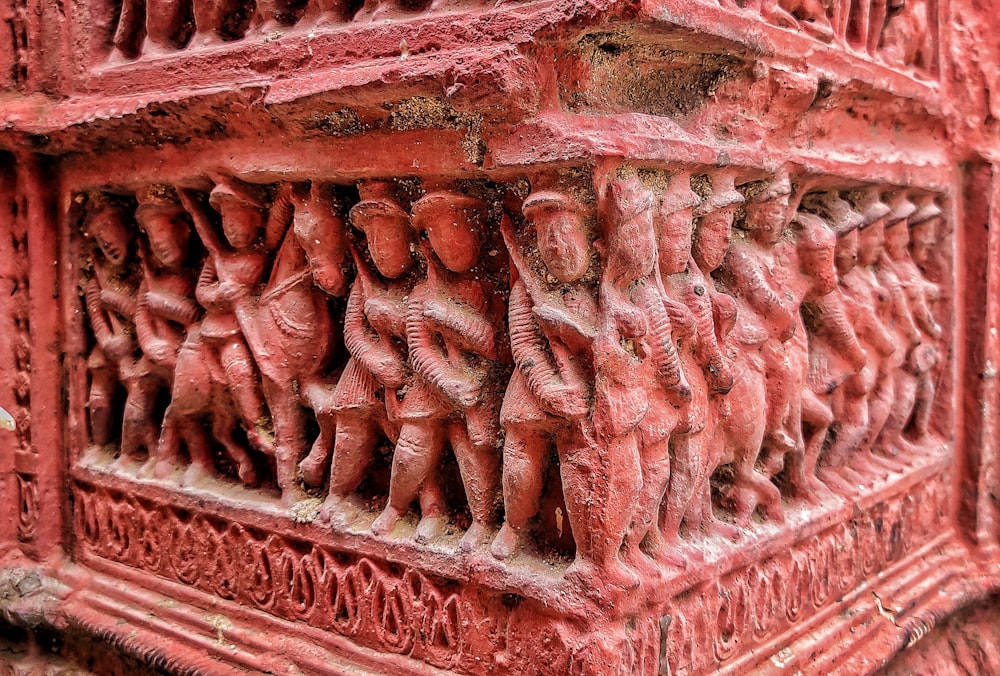 a close up of a red wall with carvings on it