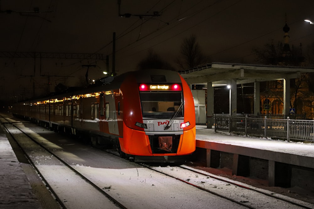 a red train traveling down train tracks at night