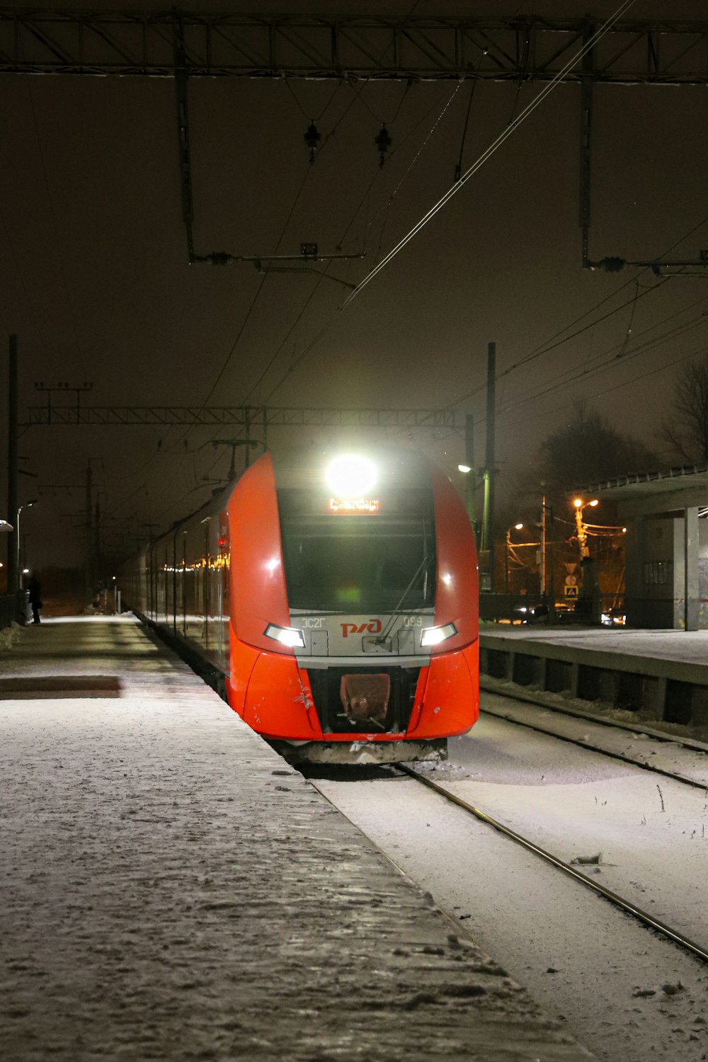 a red train traveling down train tracks at night