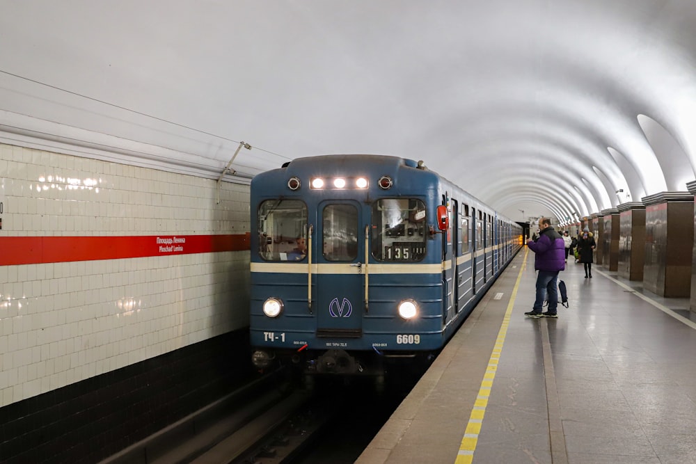 a blue train pulling into a train station