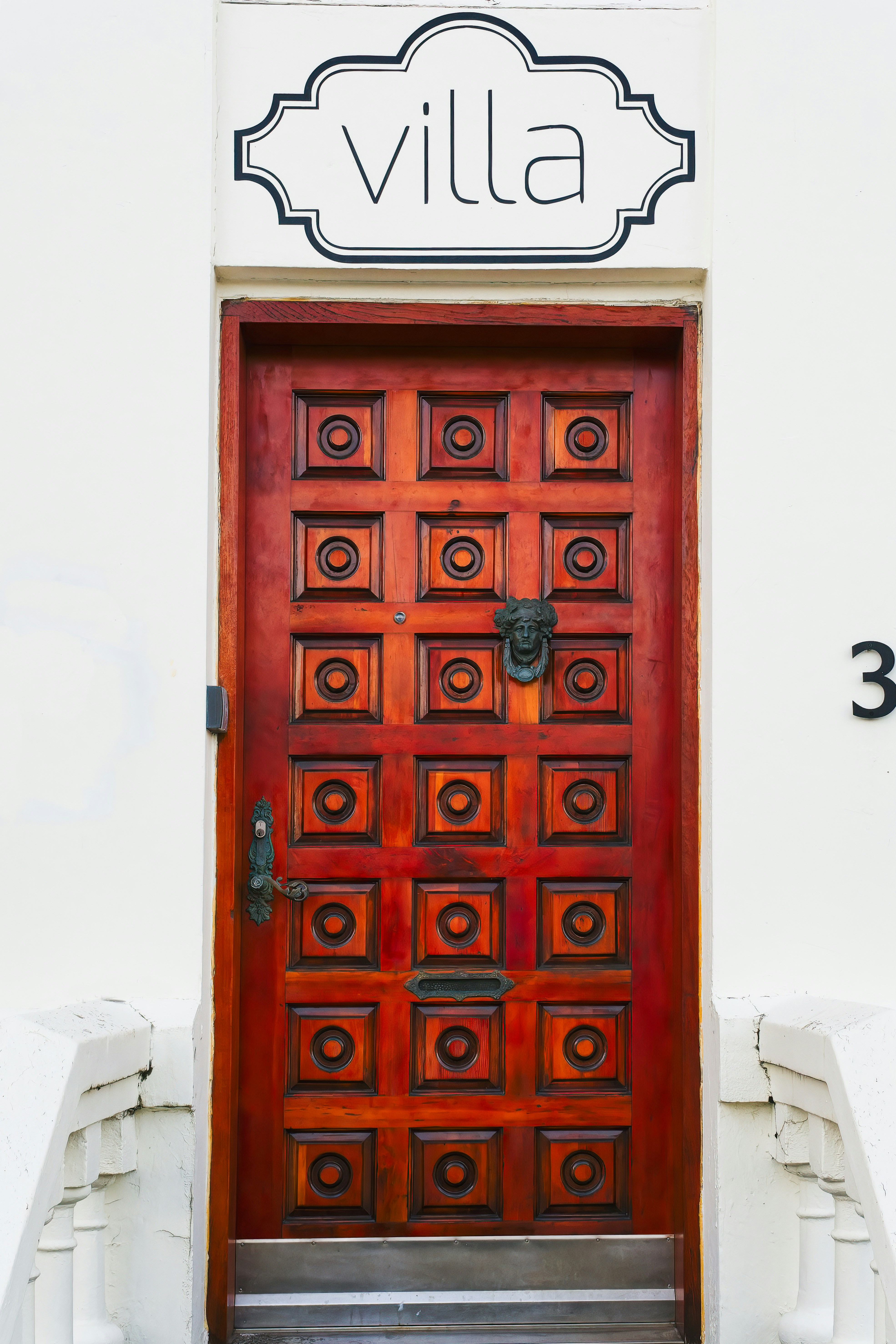 a red door with a black and white sign above it