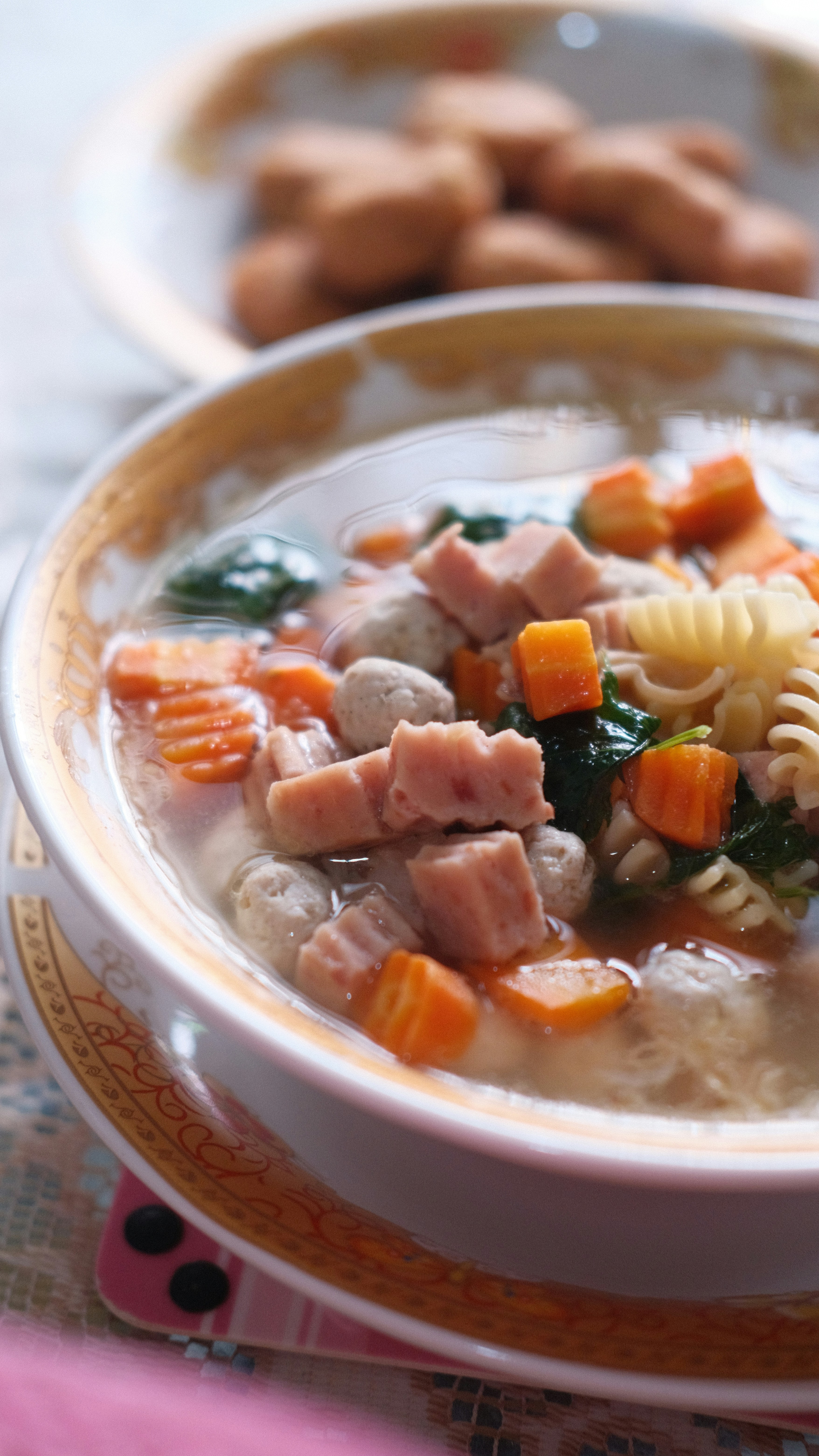 una ciotola di zuppa con pasta, prosciutto e spinaci