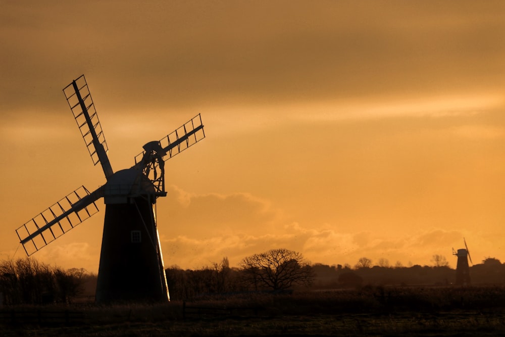 a windmill in a field with a sunset in the background