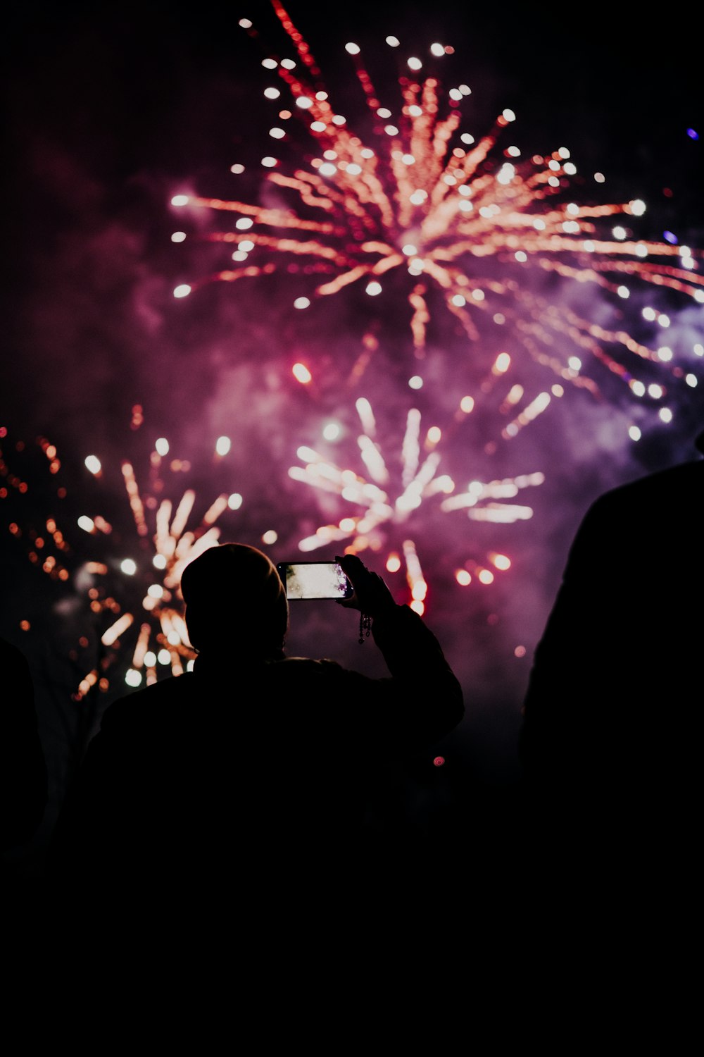 uma pessoa tirando uma foto de fogos de artifício com um telefone celular