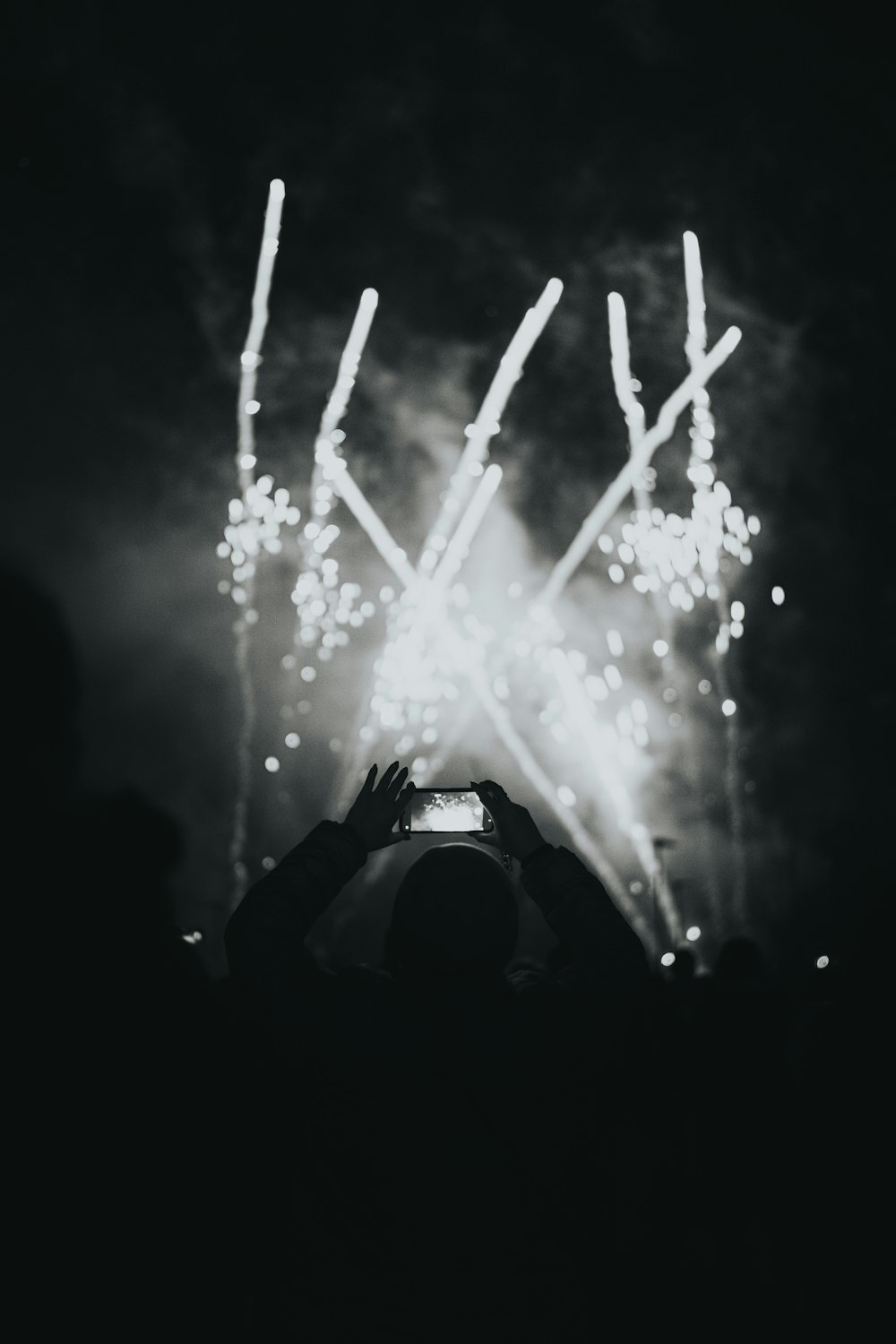 a person taking a picture of fireworks with a cell phone