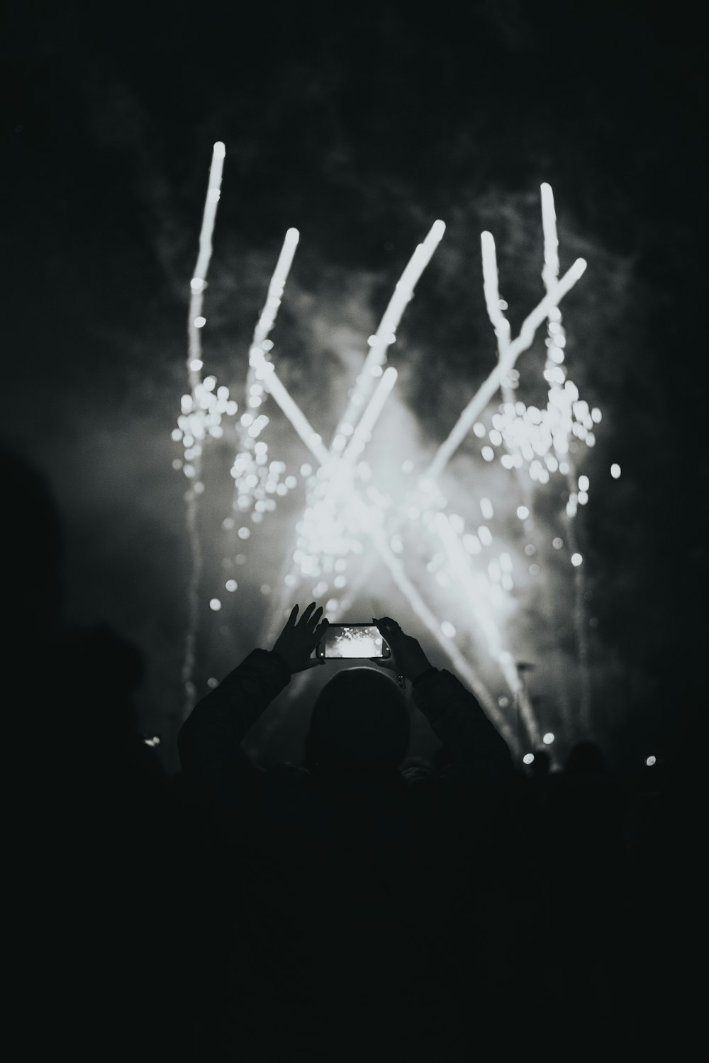 Una persona tomando una foto de fuegos artificiales con un teléfono celular