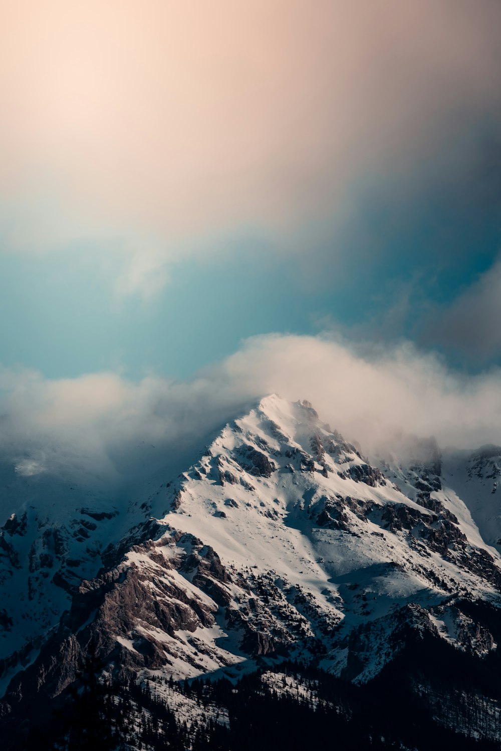 a mountain covered in snow under a cloudy sky