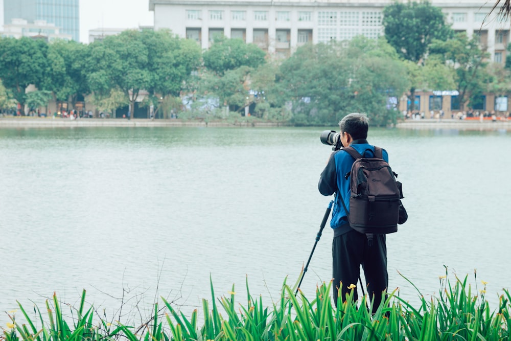 um homem tirando uma foto de um lago com uma câmera