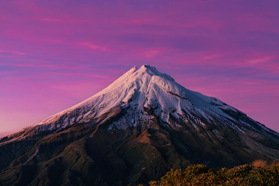 a snow covered mountain with a pink sky in the background