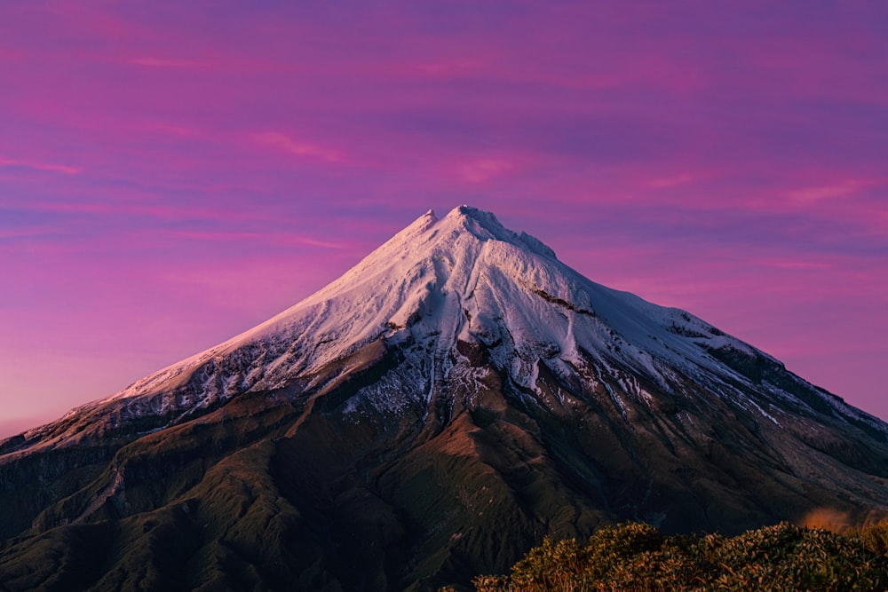 a snow covered mountain with a pink sky in the background