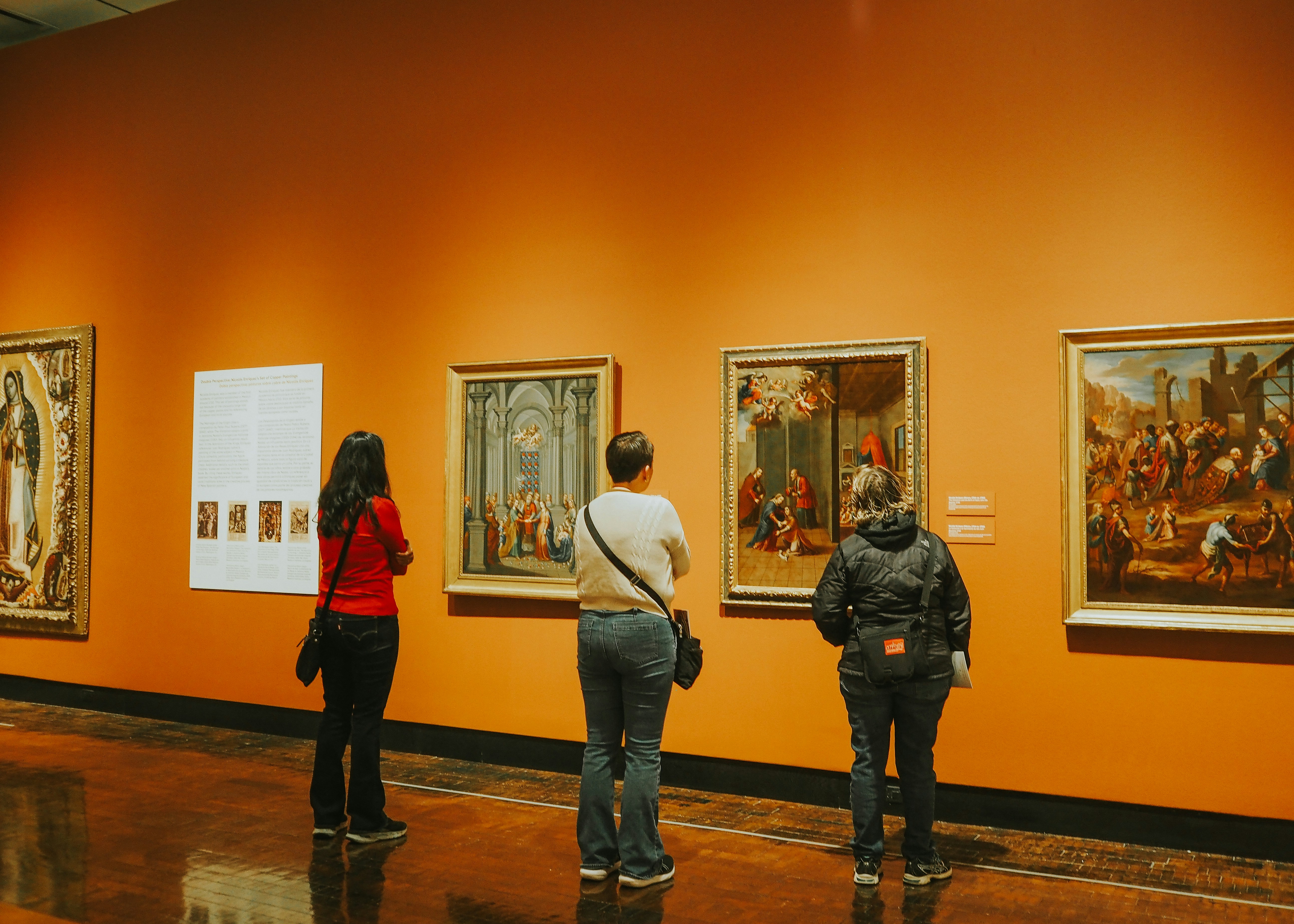 a group of people looking at paintings in a museum
